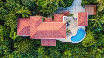 Vue aérienne d’un complexe hôtelier comprenant plusieurs bâtiments, une piscine et une végétation luxuriante.