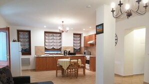 Een moderne keuken met houten kastjes, een eettafel met stoelen en een kroonluchter.