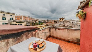A rooftop terrace with a table set for breakfast, overlooking a cityscape. - Vista Apartment in Trastevere (Roma)