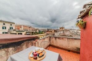 Terraço no telhado com mesa posta para o café da manhã, com vista para a paisagem urbana.
