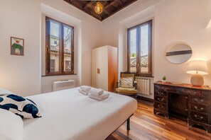 Quarto com cama, cômoda, cadeira e radiador.