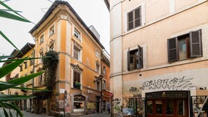 A narrow street with historic buildings, a cobblestone ground, and a closed shop with graffiti. - Vista Apartment in Trastevere (Roma)