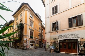 Uma rua estreita com edifícios históricos, chão de calçada e uma loja fechada com grafite.