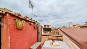 A red building with a white table and chairs, a satellite dish, and a small garden area. - Vista Apartment in Trastevere (Roma)