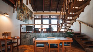 A dining area with wooden furniture, a marble wall, and a staircase. - Casa d'Abreu Neto - Siza's First Work (Matosinhos)
