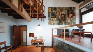 A modern interior with a dining area, wooden staircase, and a large abstract painting. - Casa d'Abreu Neto - Siza's First Work (Matosinhos)