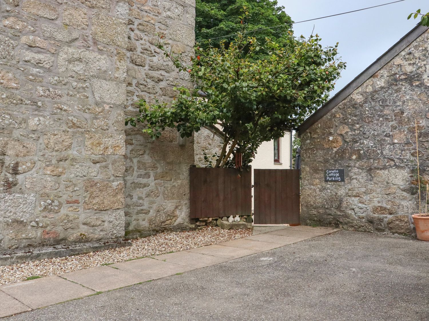 Un edificio de piedra con una puerta de madera y un cartel que indica 'Camellia Cottage Parking'.