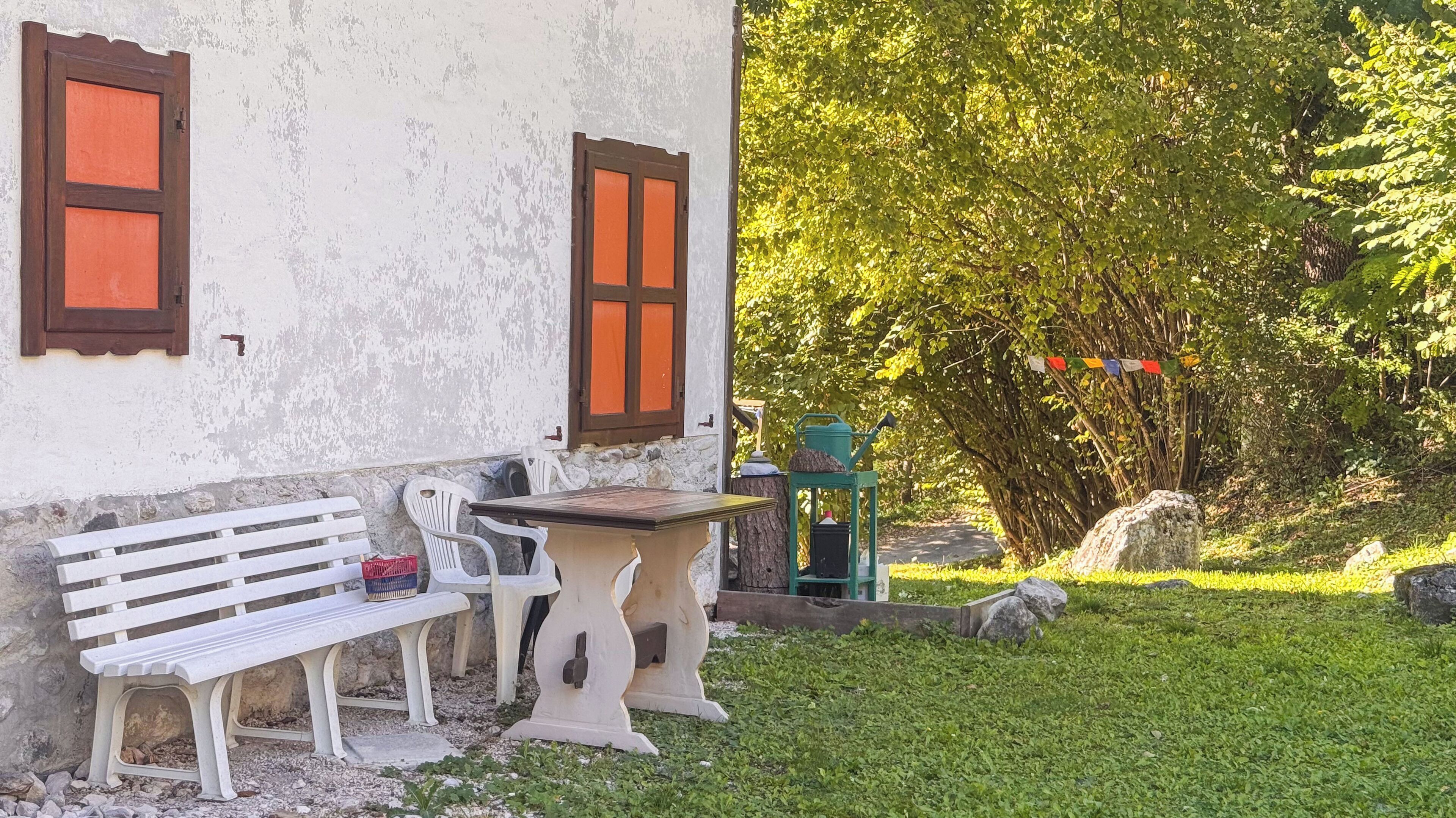A rustic outdoor seating area with a bench and two chairs, a small table, and a green lantern.