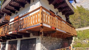 Un balcone in legno tradizionale con base in pietra, sostenuto da travi di legno.