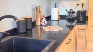 Una cucina con un piano di lavoro nero, mobili in legno, un lavello e una macchina da caffè.