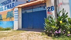 A building with a mural of a beach scene, a blue gate, and the number 28. - Pousada Sol e Mar Ilhéus (Ilhéus)