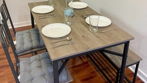 Une table à manger avec quatre assiettes blanches, deux fourchettes, deux couteaux et deux verres.