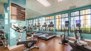 Een fitnessruimte met loopbanden, elliptische trainers en gewichten.