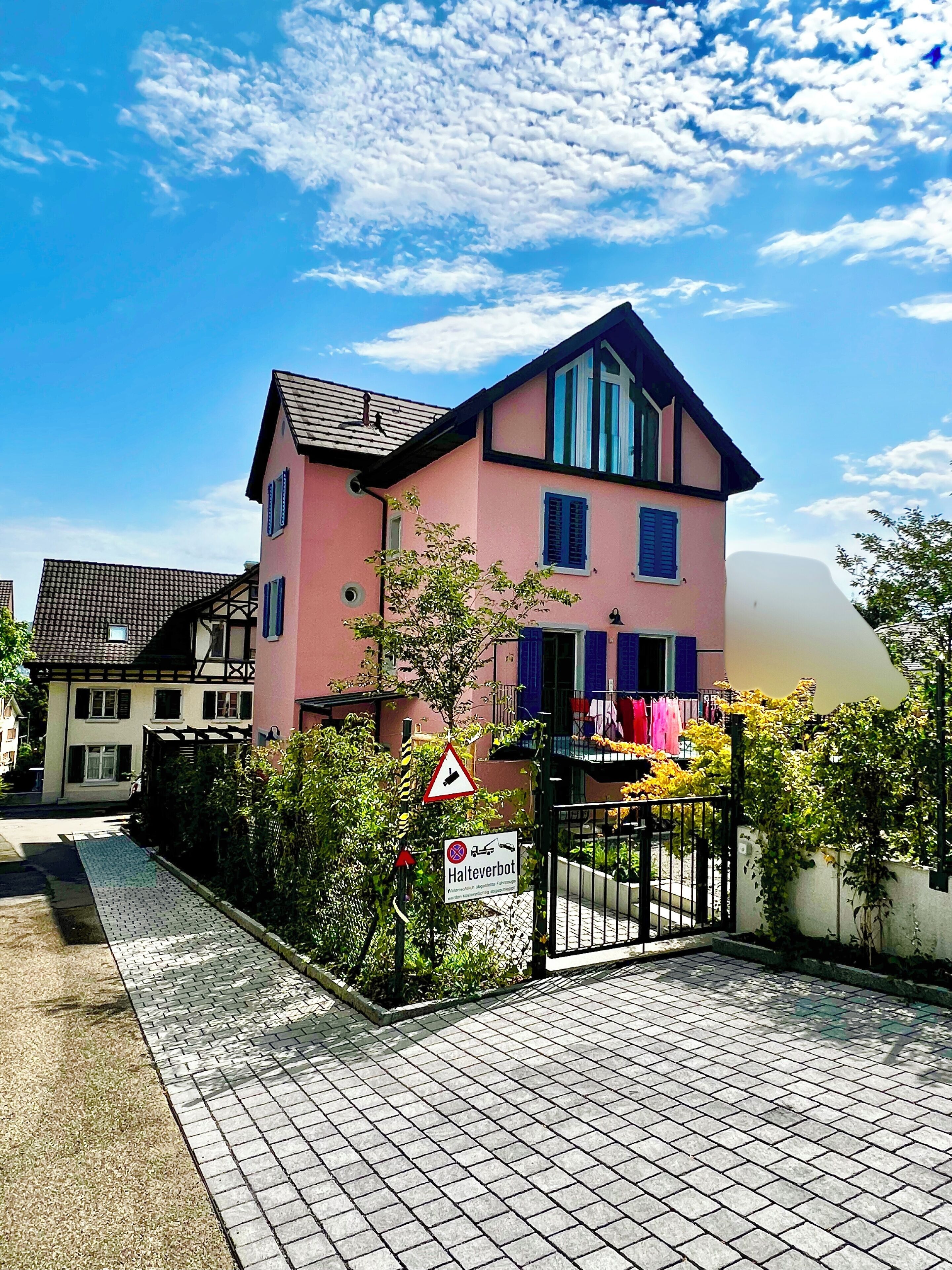 The apartment is on the ground floor of this pink house. 