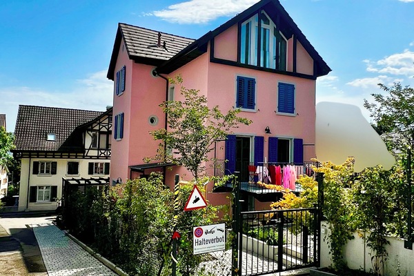 The apartment is on the ground floor of this pink house.