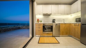 Una cocina moderna con electrodomésticos de acero inoxidable, armarios de madera y vistas al mar.