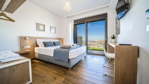 Una habitación de hotel moderna con cama, escritorio, silla y un amplio ventanal con vistas a la ciudad.