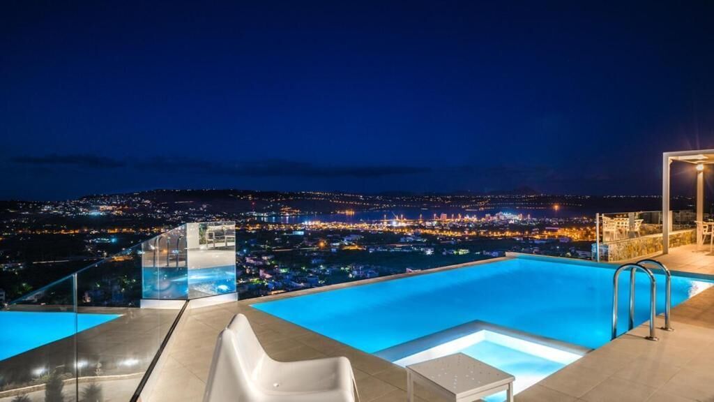 A rooftop infinity pool with a city view at night.
