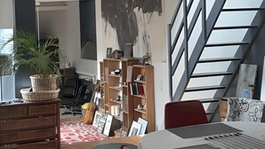 A spacious living area with a high ceiling, a staircase, and a dining area with a table and chairs. - Guest Room “La Musicale - Django Reinhardt” with Breakfast Included (Rouen)