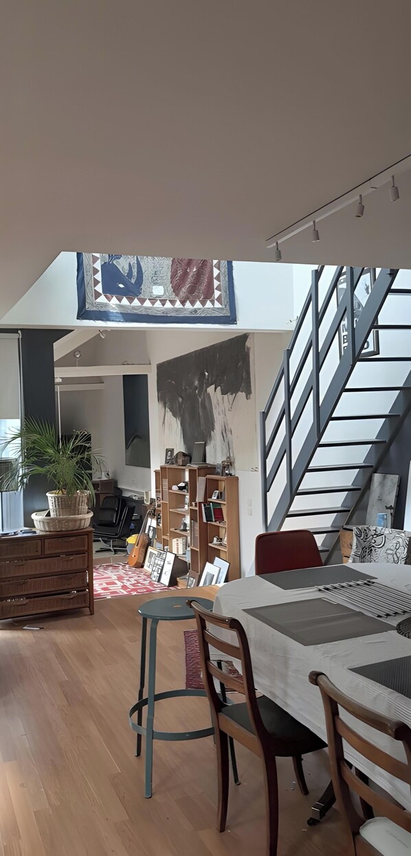 A spacious living area with a high ceiling, a staircase, and a dining area with a table and chairs. - Guest Room “La Musicale - Django Reinhardt” with Breakfast Included (Rouen)