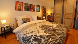 A bedroom with a bed, a nightstand, a lamp, and a bookshelf. - Guest Room “La Musicale - Django Reinhardt” with Breakfast Included (Rouen)