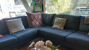 A living room with a sofa, a wooden coffee table, and a vase with flowers. - Guest Room “La Musicale - Django Reinhardt” with Breakfast Included (Rouen)