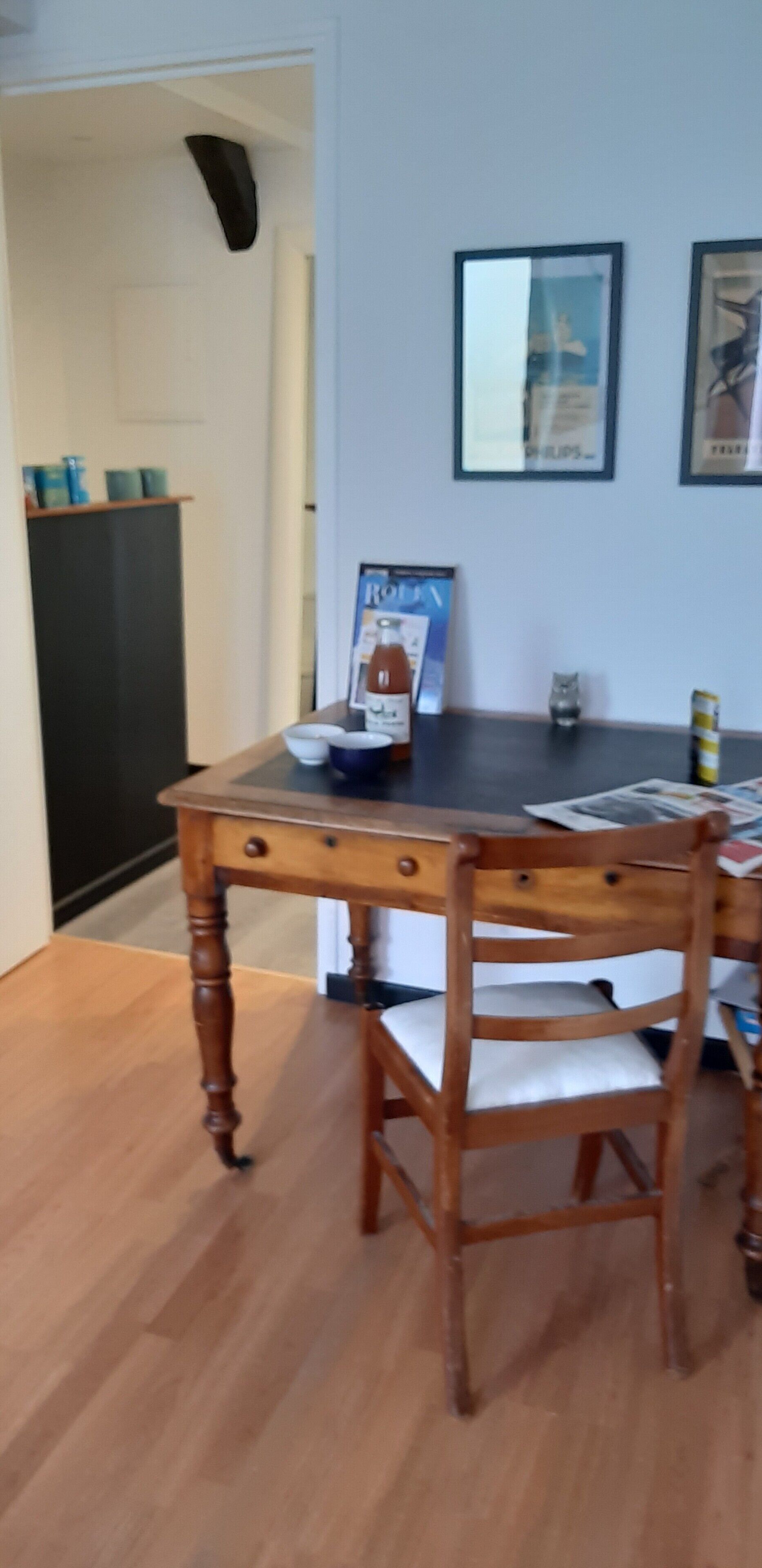 Una mesa de comedor con una silla, un cuadro en la pared y un mueble bajo en el fondo.