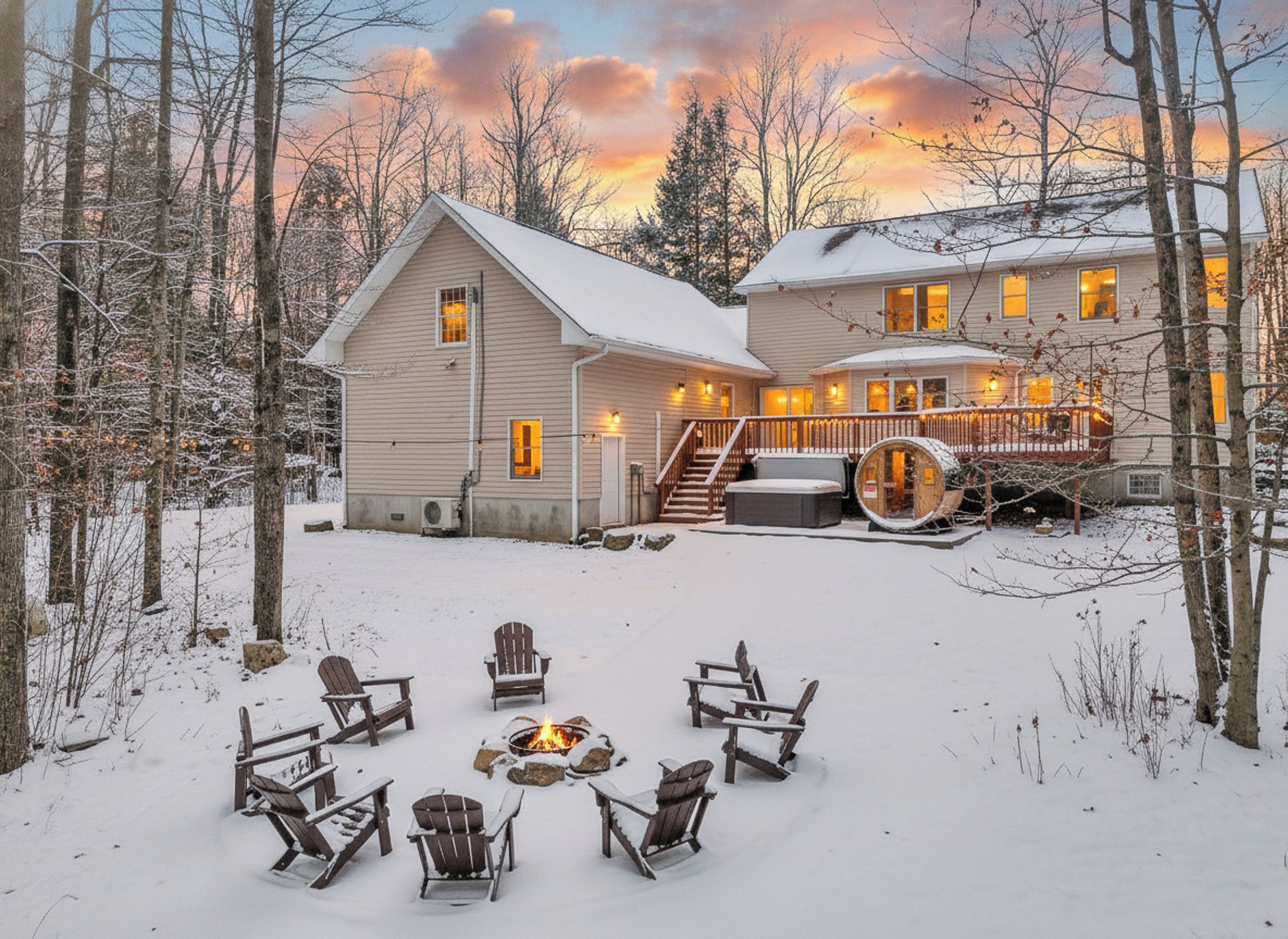 A two-story house with a deck and a fire pit in the snow.