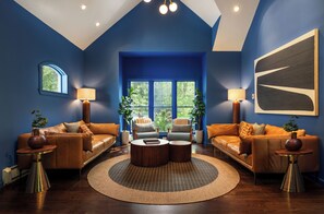 A living room with a blue wall, two sofas, a coffee table, and a large window.