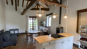 A spacious kitchen with wooden beams, a central island with a sink, and pendant lighting. - Holiday Home 'La P'tite Maiz' with Shared Pool, Private Terrace & Wi-Fi (Bourg-de-Visa)