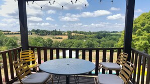 A covered outdoor seating area with a round table and four chairs, overlooking a green landscape. - Holiday Home 'La P'tite Maiz' with Shared Pool, Private Terrace & Wi-Fi (Bourg-de-Visa)
