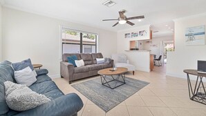 Un salon moderne avec un canapé gris, une table basse et un ventilateur de plafond.