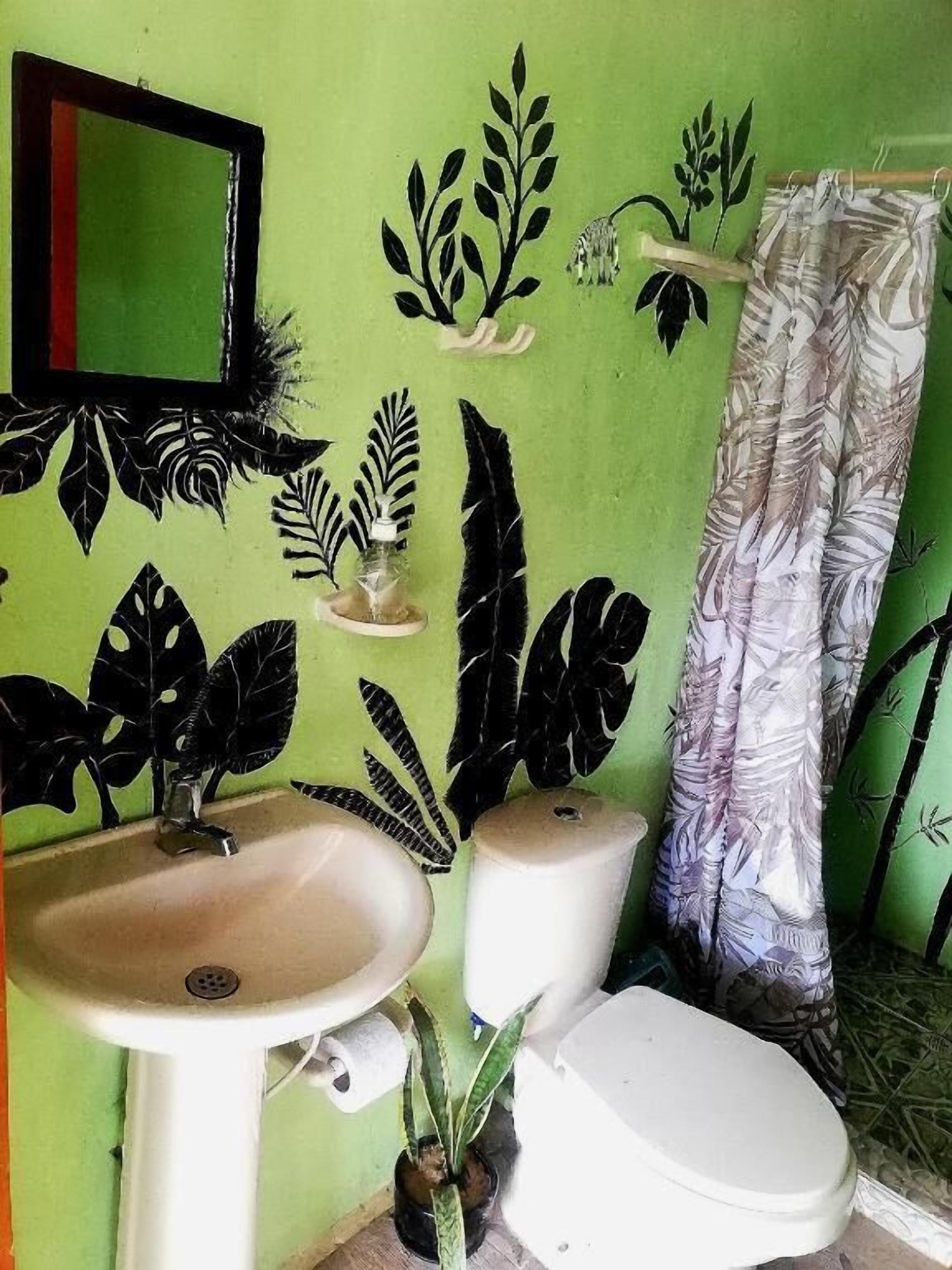 A bathroom with a green wall, a white sink, a toilet, and a shower curtain.