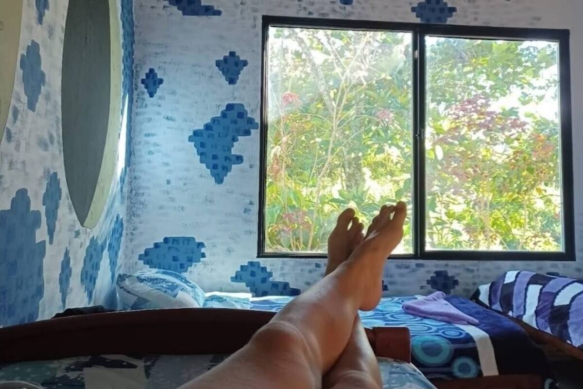 Une pièce avec un lit, une fenêtre et un mur orné d’un motif géométrique.