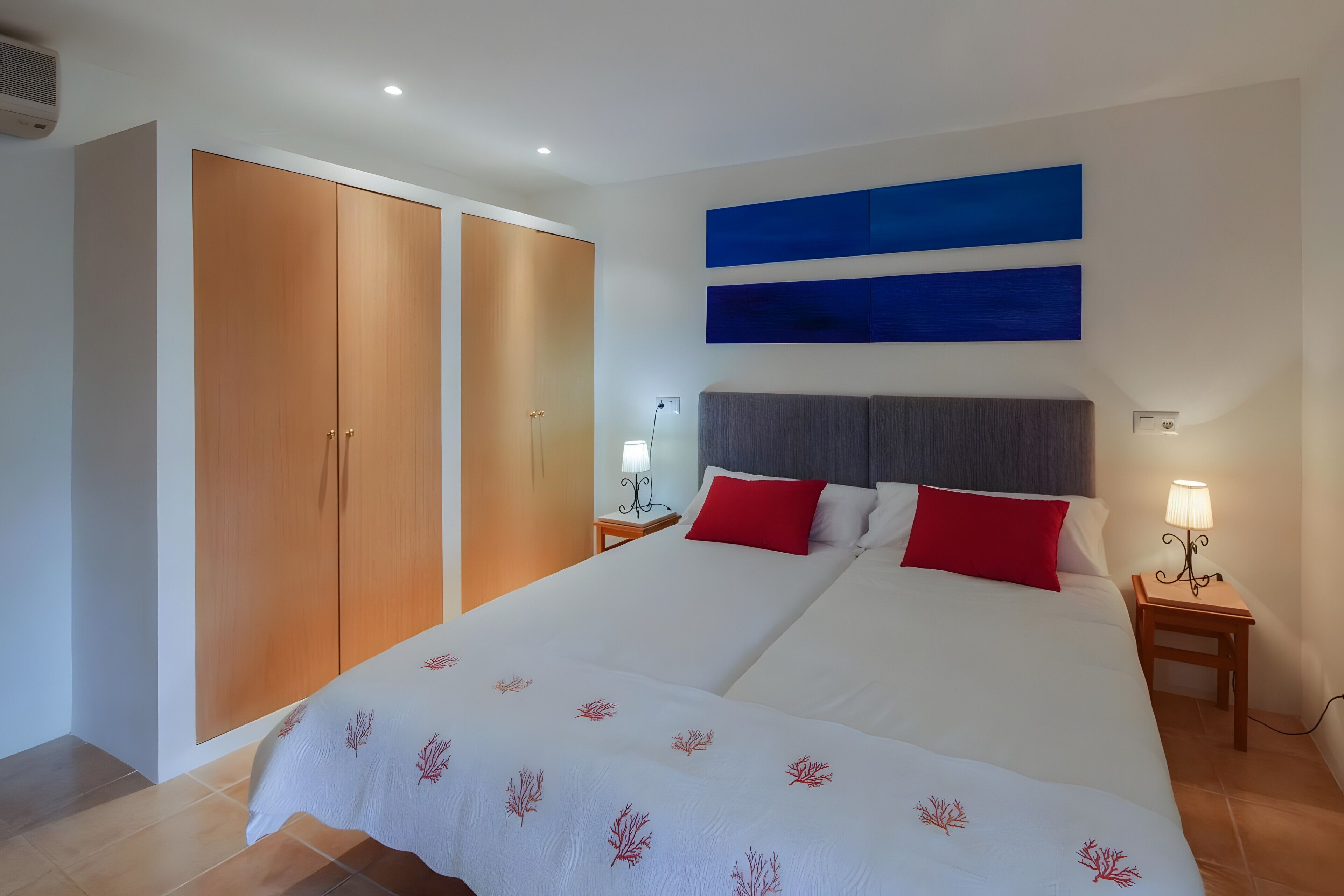 A bedroom with a bed, two nightstands, a wardrobe, and a wall-mounted artwork.