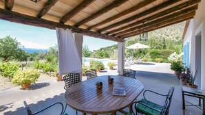 Une terrasse extérieure avec une table ronde en bois, des chaises vertes et des plantes en pot.