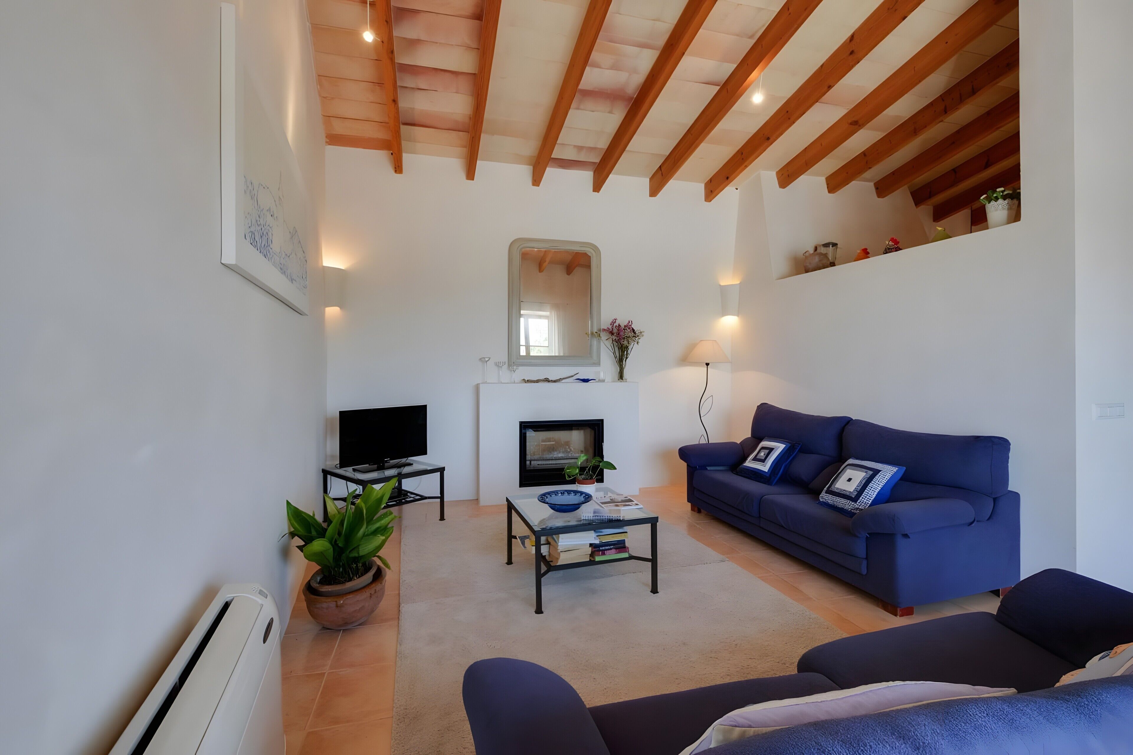 Ein Wohnzimmer mit Kamin, Sofa, Fernseher und Couchtisch.