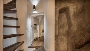 Una escalera de madera conduce a una habitación con un radiador blanco y una planta en maceta.