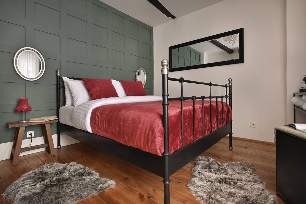 Un dormitorio moderno con cama, espejo, mesita de noche y cómoda.