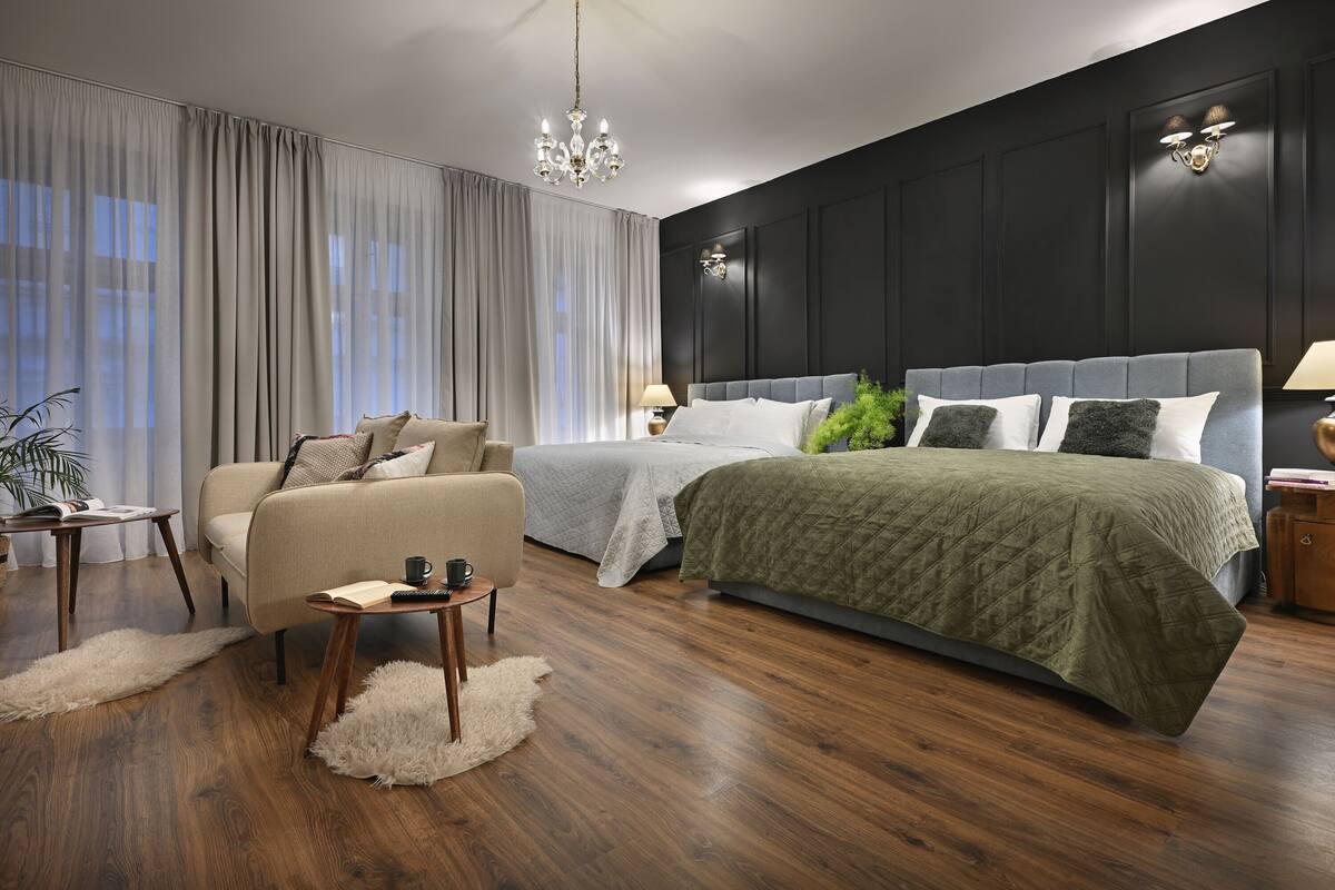 Un dormitorio moderno con una cama grande, un sofá, una mesita y una araña.