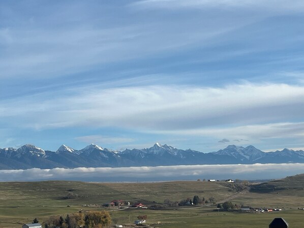 Un paisaje montañoso con un pueblo en primer plano y cumbres nevadas al fondo.
