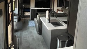 Una cocina moderna con una isla central, electrodomésticos integrados y una lámpara colgante.