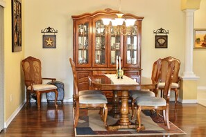 A dining room with a wooden table, four chairs, a large wooden cabinet, and a chandelier. - 3/2 Designer in the Village of Hadley (The Villages)
