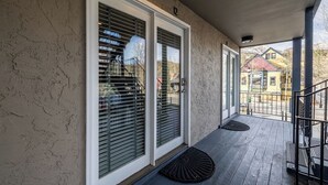 A covered porch with large sliding glass doors, a metal railing, and a black doormat. - Prime Main Street location in Breckenridge (Breckenridge)