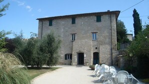 A stone building with a paved entrance and outdoor seating. - Ostello della Pace Assisi (Assisi)