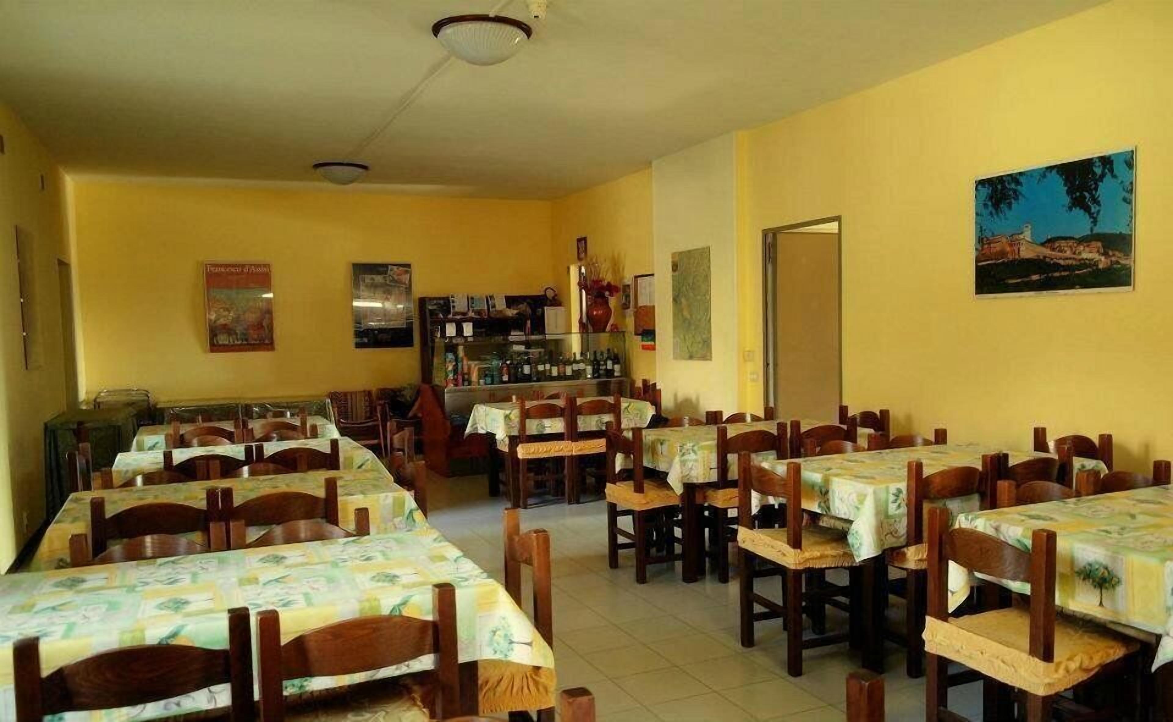 Un comedor con varias mesas y sillas, una zona de bar con botellas y un cuadro en la pared.