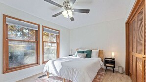 A bedroom with a bed, a ceiling fan, a nightstand, and a window. - Tunnel Vision Trail House Bike In Bike Out (Bella Vista)