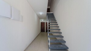 A narrow, tiled hallway with a modern staircase. - Apt w/ 1 Bedroom and Air Conditioning Irn0103 (Florianópolis)