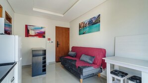 A modern living room with a sofa, a small table, and a refrigerator. - Apt w/ 1 Bedroom and Air Conditioning Irn0103 (Florianópolis)