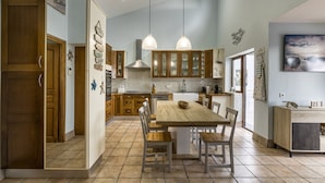 Una cocina moderna con armarios de madera, una isla central, iluminación colgante y un ventanal grande.